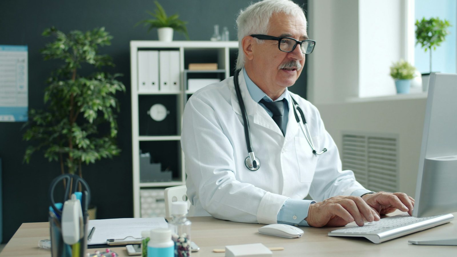 A doctor working at the computer in their consulting room